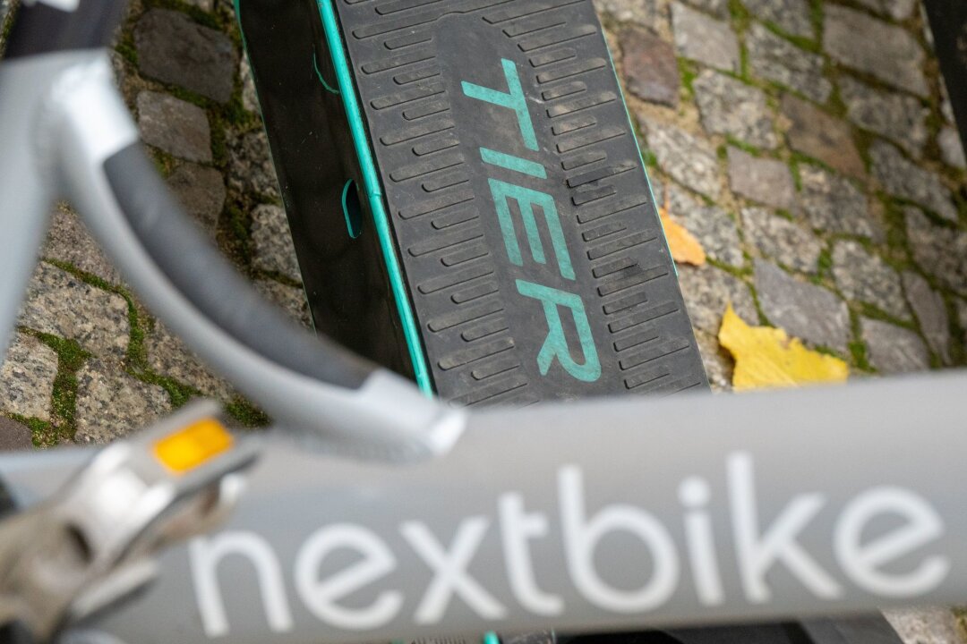Englischer Investor übernimmt Leihradanbieter Nextbike - E-Tretroller des Anbieters Tier und ein Leihfahrrad von Nextbike stehen nebeneinander auf einem Gehweg.