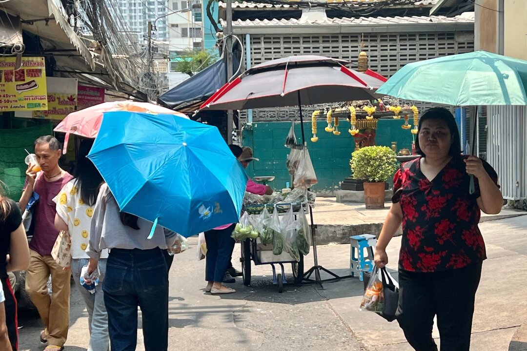 Extremhitze auf den Philippinen - Schulen schließen - Menschen schützen sich in Bangkok mit Schirmen vor der extremen Hitze und vor der Sonne. Nicht nur in Thailand, sondern auch auf den Philippinen leiden die Menschen derzeit unter den hohen Temperaturen.