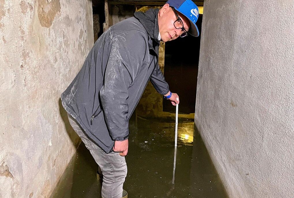 Keller in Aue steht regelmäßig unter Wasser: Rechtsstreit seit 2007 - Herr Melech Hendrik (51) misst die Tiefe im überlfuteten Keller. Foto: Daniel Unger