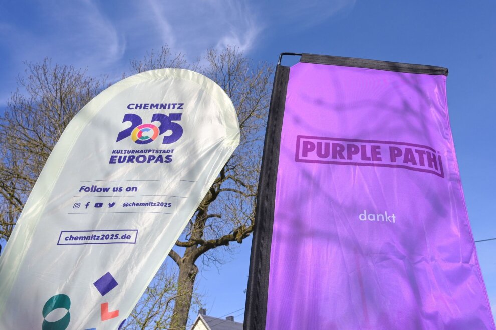 Kulturhauptstadt: Neues Kunstwerk am Skulpturenweg - Zwei Flaggen "Chemnitz 2025, Kulturhauptstadt Europas" und "Purple Path" stehen nebeneinander.