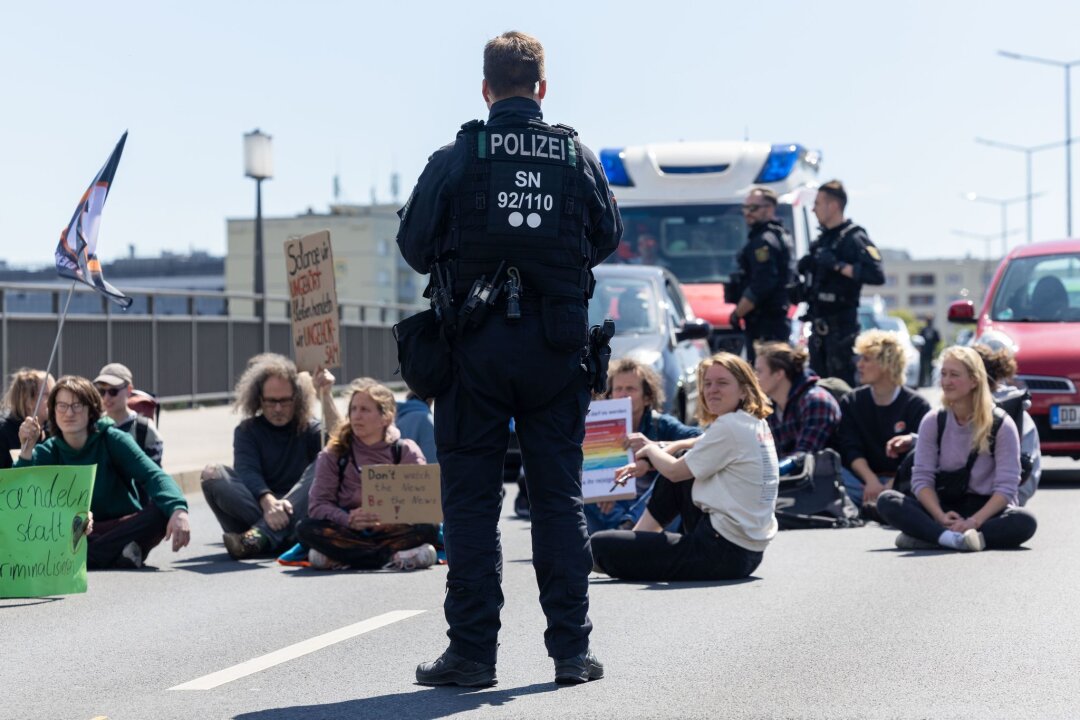 Letzte Generation blockiert Carolabrücke in Dresden - Ein Polizist beobachtet Klimaaktivisten auf der Dresdner Carolabrücke.