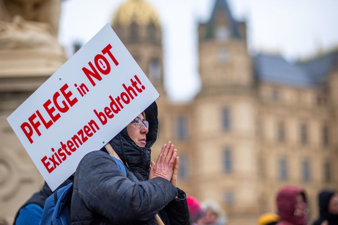Mangel an Ärzten und Pflegekräften droht zu wachsen - Bei einer Protestaktion vor dem Schweriner Landtag hält eine Teilnehmerin ein Schild mit der Aufschrift "Pflege in Not - Existenzen bedroht!".