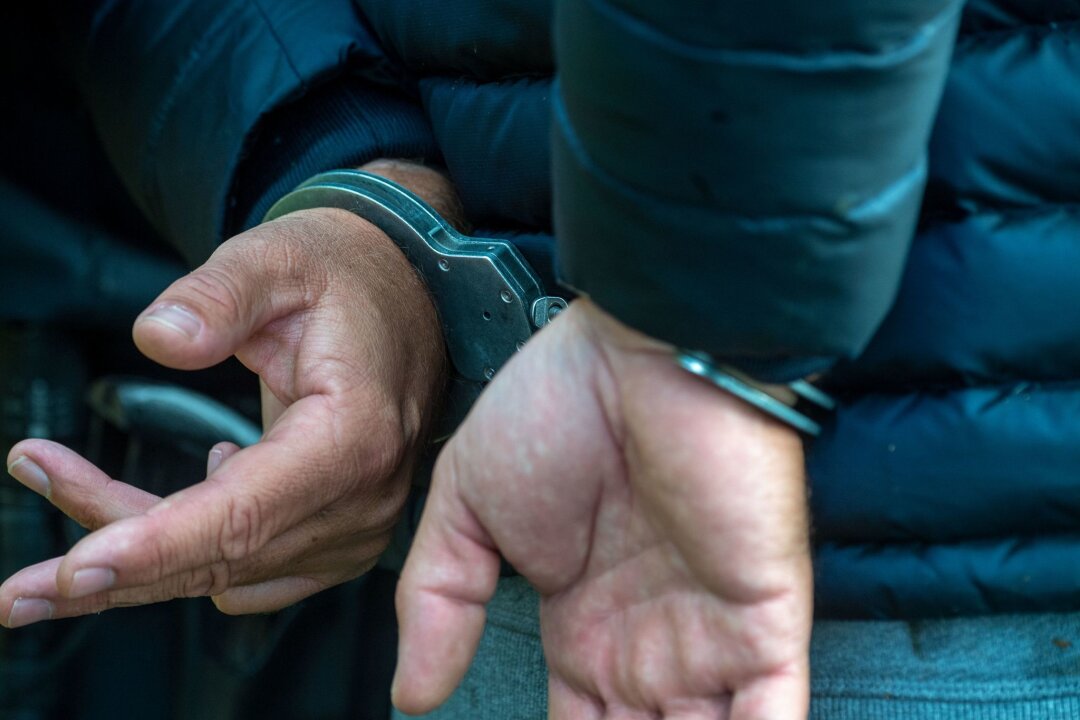 Nach gewaltsamem Tod eines 69-Jährigen: Zwei Festnahmen - Ein Mann trägt Handschellen.