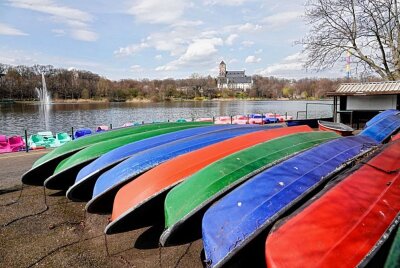 Spaziergänger genießen das Wetter am Chemnitzer Schlossteich - Boote warten auf ihren Einsatz. Foto: Harry Haertel