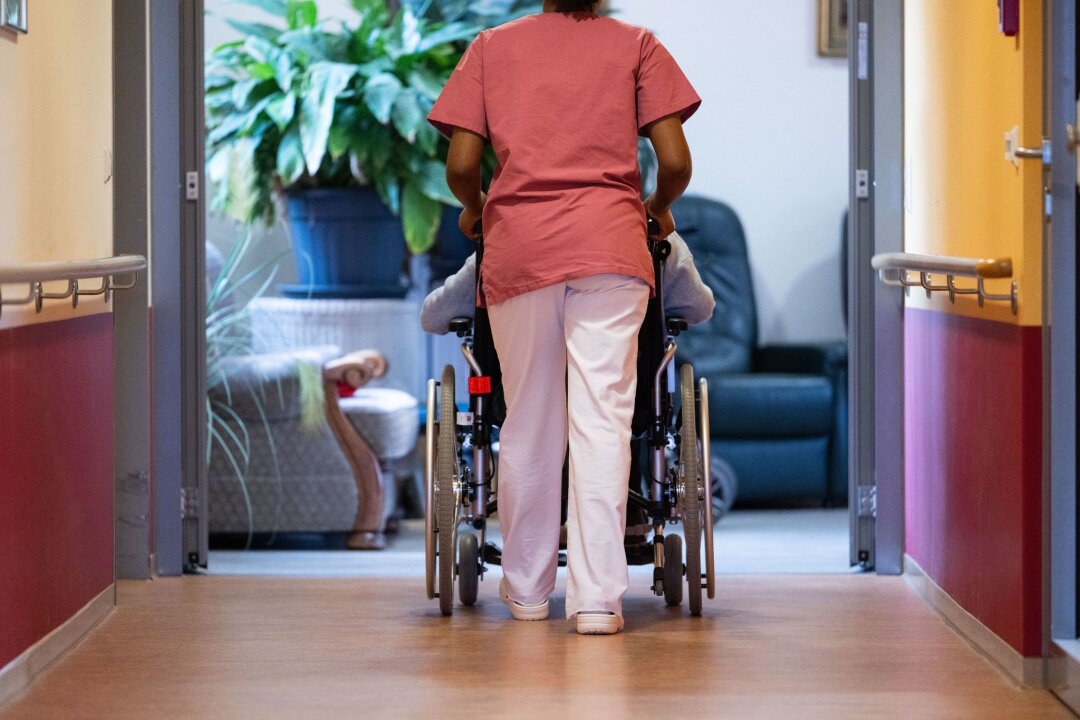 Tag der Pflege: AWO warnt vor wachsender Altersarmut - Eine Bewohnerin eines Pflegeheims wird von einer Pflegerin einen Gang entlang geschoben.