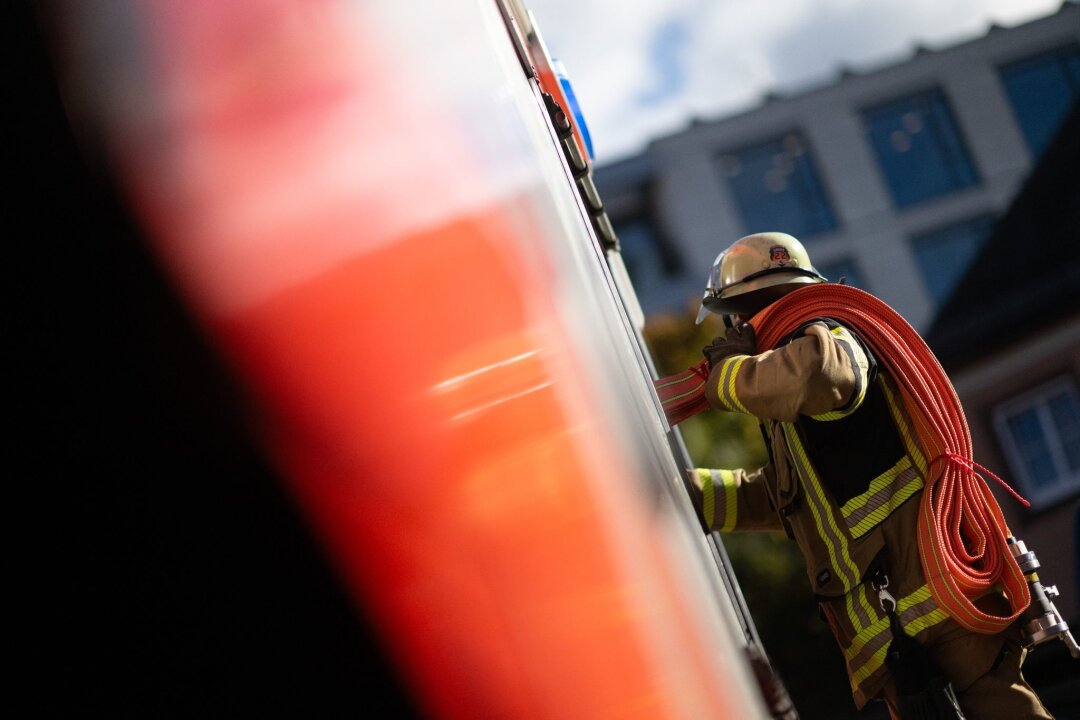 Unbekannte legen Feuer in Dresdner Heide: Polizei ermittelt - Eine Einsatzkraft der Feuerwehr nimmt während eines Pressetermins einen Schlauch aus einem Einsatzfahrzeug.