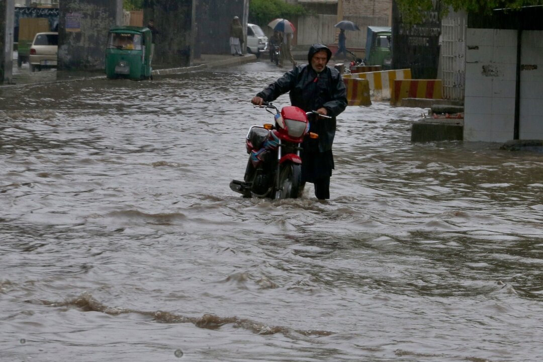 Viele Tote bei Unwettern in Afghanistan und Pakistan - Ein Pakistaner watet nach starken Regenfällen mit seinem Motorrad durch eine überschwemmte Straße in Peschawar.