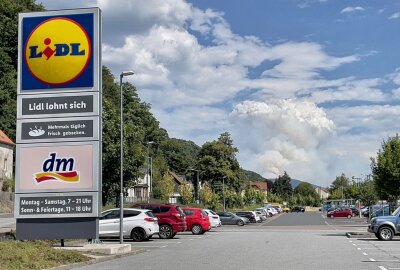 Waldbrand Sächsische Schweiz: Lage unter Kontrolle? Drohnenbilder klären auf - Eine kilometerhohe Rauchwolke zieht hinter einem Parkplatz auf (Dienstag). Foto: Daniel Unger