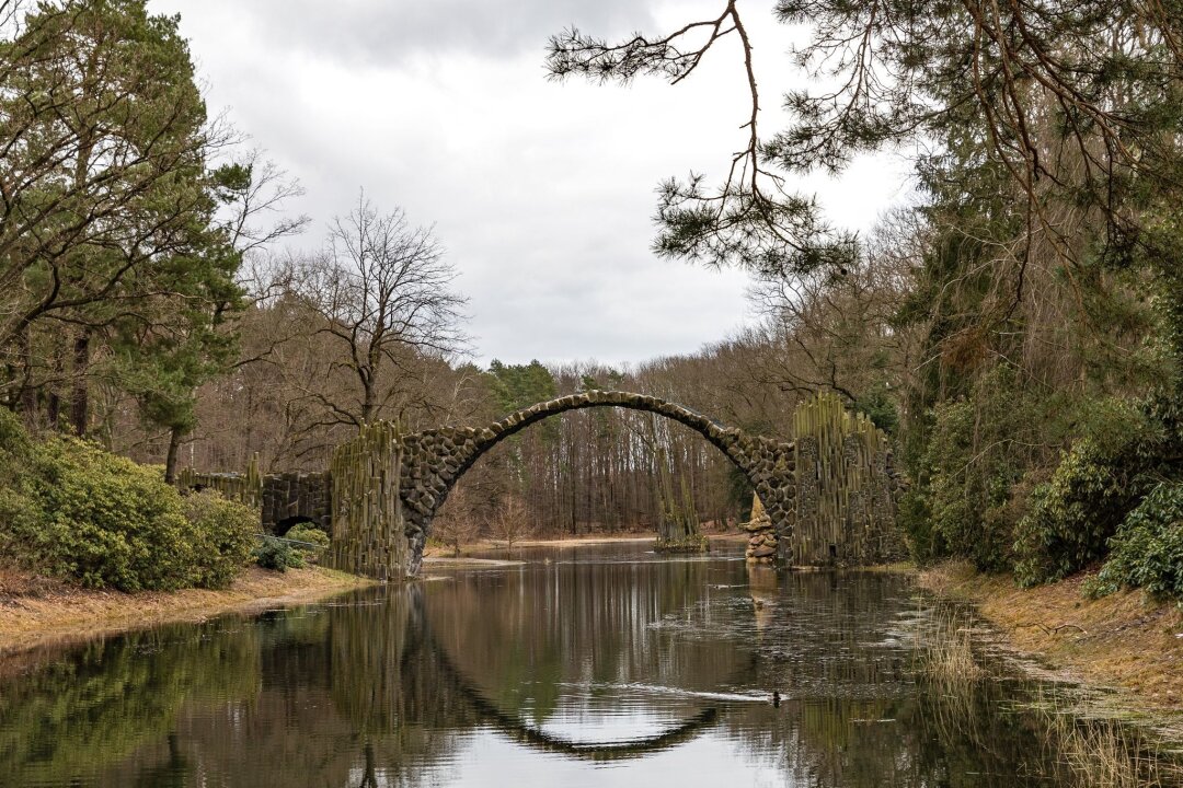 Der KunstBus ist in der Oberlausitz unterwegs - Die Rakotzbrücke aus Basaltsteinen im Kromlauer Rhododendronpark spiegelt sich bei bedecktem Wetter im Rakotzsee.
