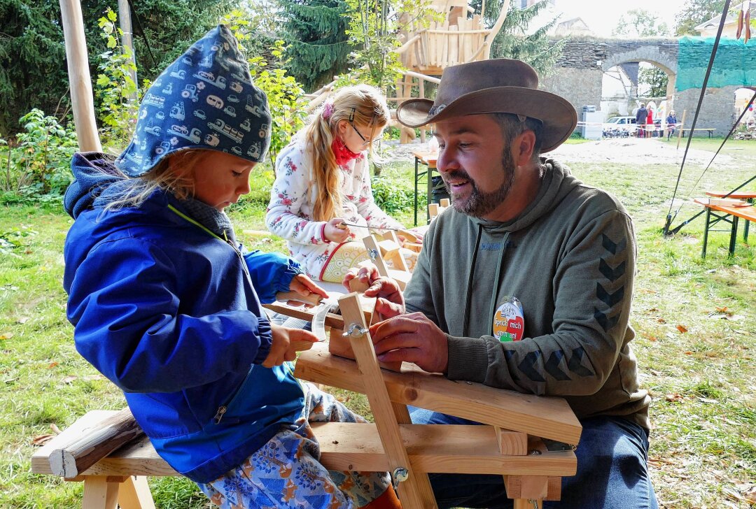 Abenteuer-Schule Erzgebirge weckt großes Interesse - Lernbegleiter Michael Schreiber präsentiert Kindern die Holzwerkstatt unter freiem Himmel. Foto: Andreas Bauer