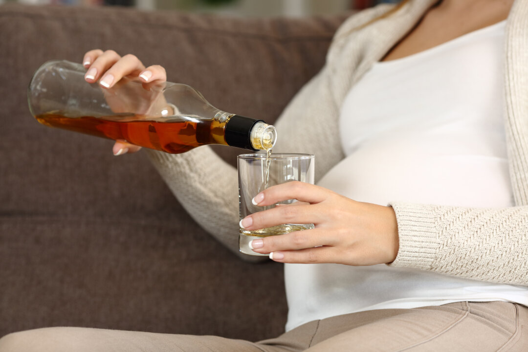 Schwangere Frau gießt sich Wein ein.