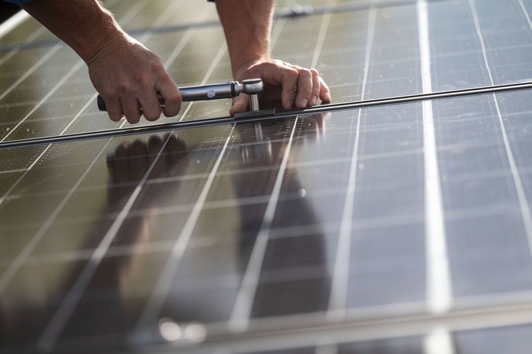 Ampel-Fraktionen uneins bei Förderung deutscher Solarfirmen - Mitarbeiter einer Firma montieren Photovoltaikmodule auf dem Dach eines Wohnhauses.