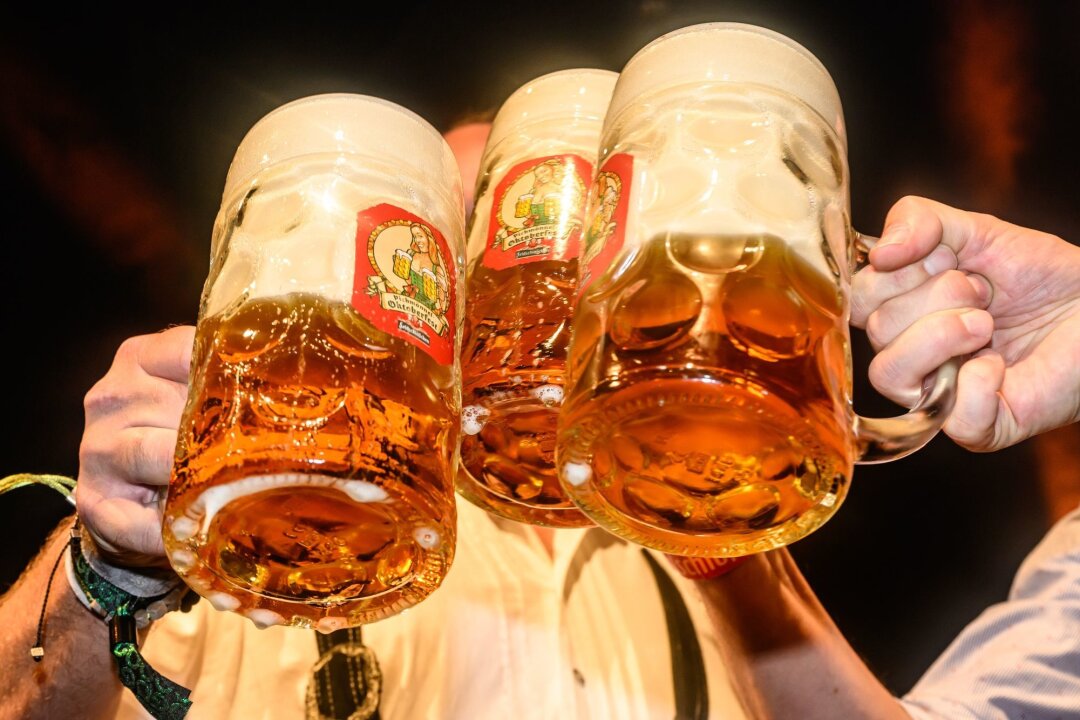 Bierabsatz rückläufig - Branche für 2024 zuversichtlich - Mit Maßkrügen wird am traditionellen Fassbieranstich zum Dresdner Oktoberfest angestoßen.