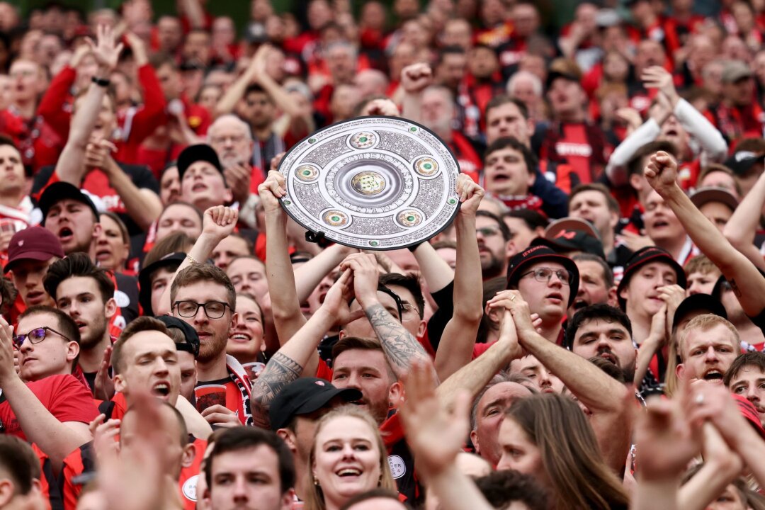 Der Bayer-Spielfilm zur deutschen Meisterschaft - Fußball: Ein Leverkusener Fan hält während des Spiels eine Nachbildung der Meisterschale in den Händen. Bayer Leverkusen gewinnt die Deutsche Meisterschaft.