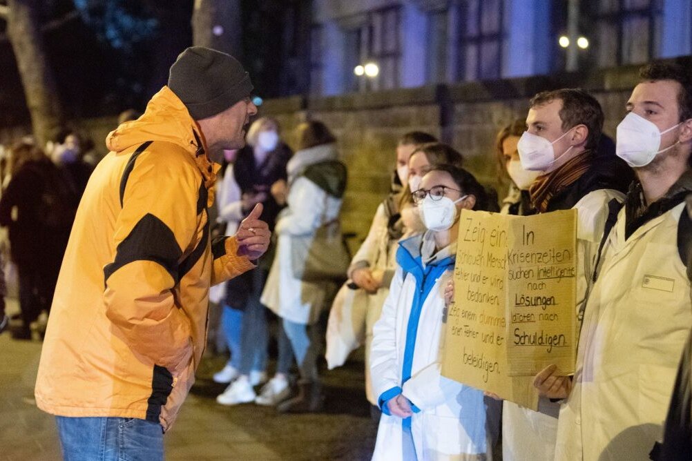 Ein Teilnehmer einer als «Spaziergang» deklarierten Demonstration von Impfgegnern und Kritikern der Corona-Maßnahmen steht am Universitätsklinikum Dresden vor zahlreichen Gegendemonstranten.