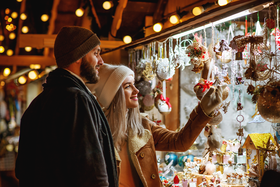 Paar steht auf dem Weihnachtsmarkt vor weihnachtlich geschmückter Bude