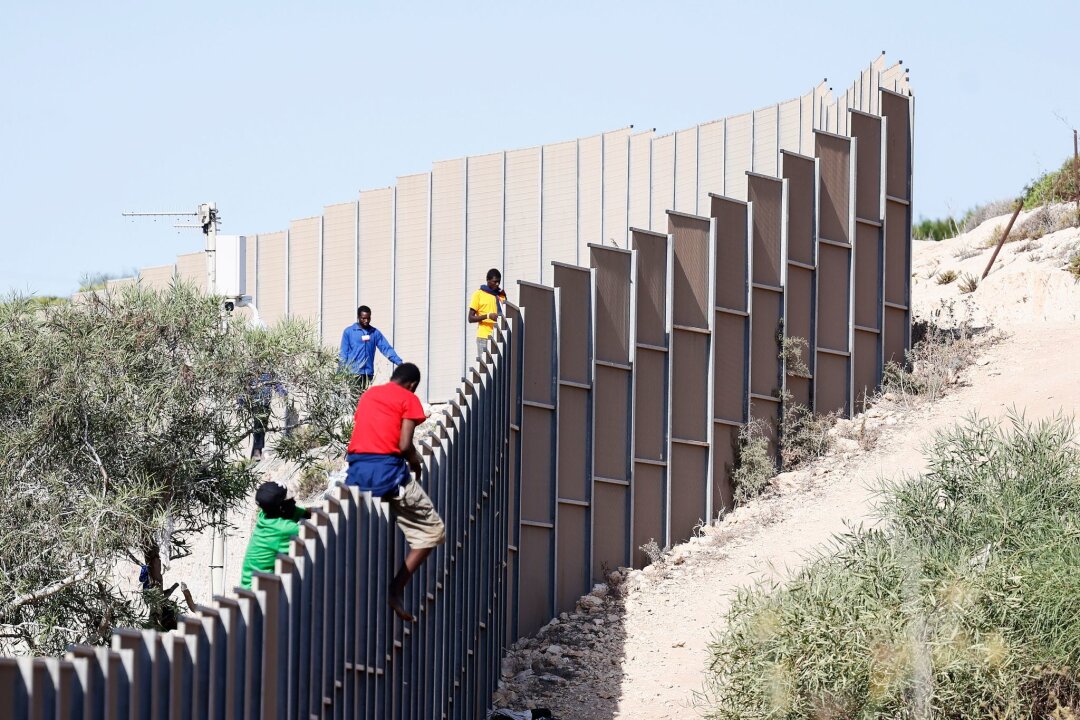 EU-Parlament stimmt für Asylreform: Was ändert sich? - Migranten klettern über einen Zaun auf der Insel Lampedusa.