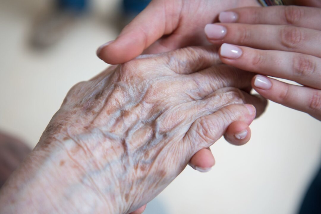 Fast jede fünfte Pflege-Fachkraft in zehn Jahren in Rente - Eine Pflegerin hält die Hand einer Bewohnerin im Seniorenzentrum.