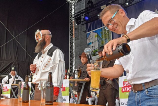 Moderator Gerd Edler füllt das Glas, Uwe Debes aus Olbernhau wartet auf den Einsatz am Verkostungstisch, Augen verhüllt. Foto: Christof Heyden