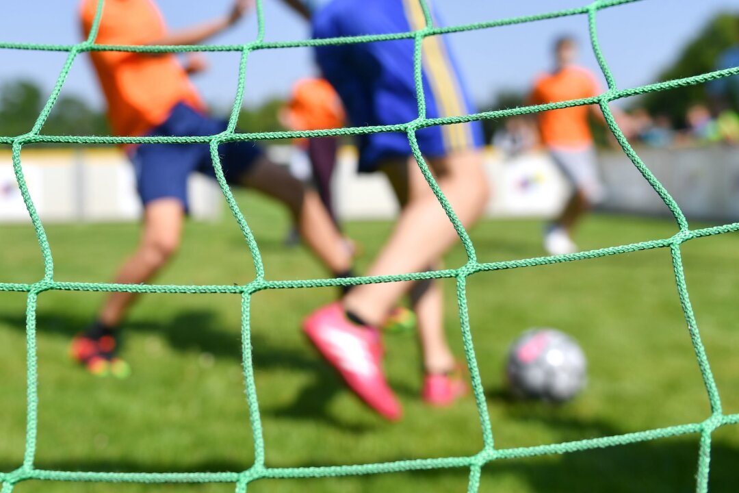 "Für starke Kinder": Evangelische Kirche sammelt Spenden - Kinder spielen auf einem Sportplatz Fußball.