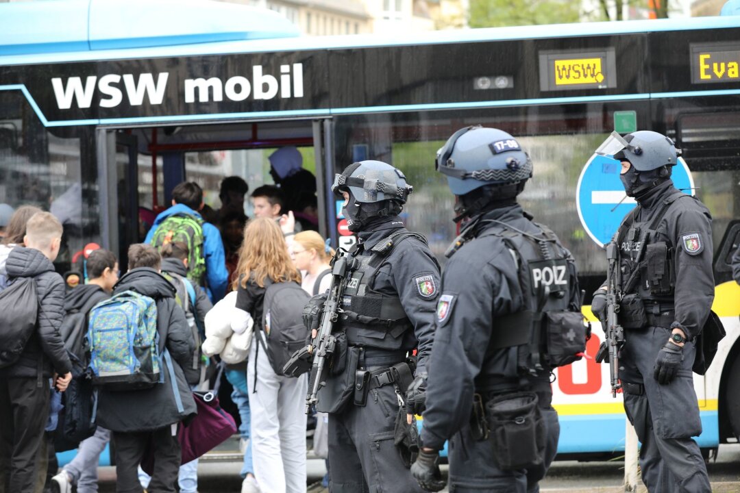Großeinsatz an Wuppertaler Gymnasium nach Notruf - Polizisten führen Schüler in Wuppertal aus dem Gebäude in einen Evakuierungsbus.