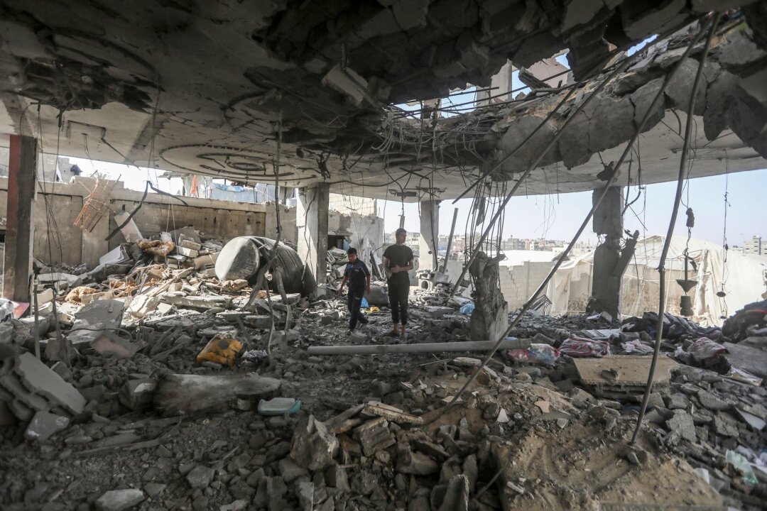 Hamas signalisiert Einlenken vor Gaza-Verhandlung - Palästinenser stehen in den Trümmern eines Hauses nach einem israelischen Luftangriff, bei dem mehrere Menschen getötet wurden.