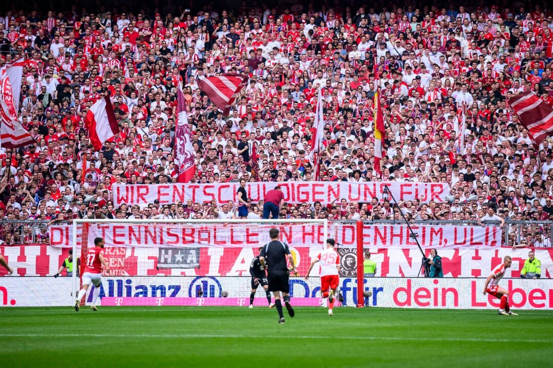 Humorvoller Konter der Bayern-Fans auf Hoeneß-Kritik - Die Bayern halten ein Transparent mit der Aufschrift "Wir entschuldigen und für die Tennisbälle in Heidenheim, Uli!" in die Luft.