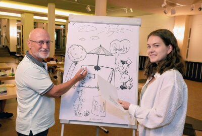 Im Workshop sind Cartoons entstanden - Workshop-Leiter Stephan Buße (li.) erklärt Anne Schmiedt etwas zur Zeichentechnik. Foto: Ralf Wendland