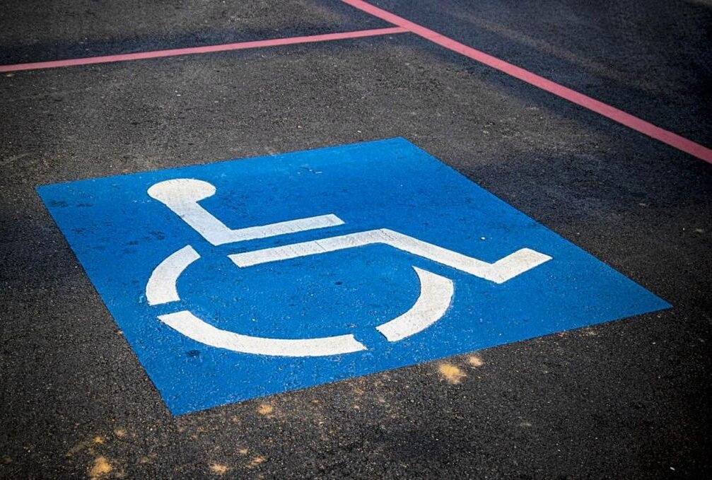 Symbolbild. Ein Rollstuhl-Symbol kennzeichnet einen Behindertenparkplatz. Foto: AbsolutVision / Pixabay