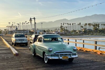 Kalifornien kulinarisch: Food-Trucks und Gourmet-Sterne - "California dreamin'": Ein schicker Oldtimer fährt auf dem Pier in Santa Barbara vor palmengesäumten Hintergrund.