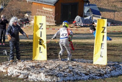 Kein Schnee? In diesem Erzgebirgsdorf wurde der Skifasching trotzdem zu einer großen Party - Ein mutiger Nachwuchssportler rannte mit Skiern den Hang herunter - hin zum letzten Rest Schnee. Foto: Andreas Bauer