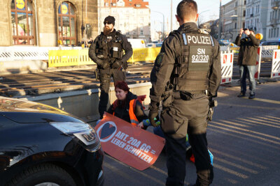 Klimaaktivisten verkleben sich im Berufsverkehr auf Straße miteinander - Klima-Aktivisten setzten sich auf die Fahrbahn in Dresden. Foto: xcitepress