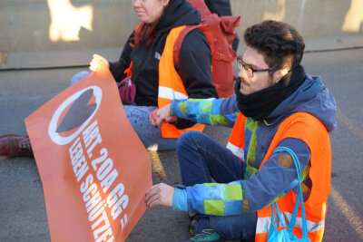 Klimaaktivisten verkleben sich im Berufsverkehr auf Straße miteinander - Klima-Aktivisten setzten sich auf die Fahrbahn in Dresden. Foto: xcitepress