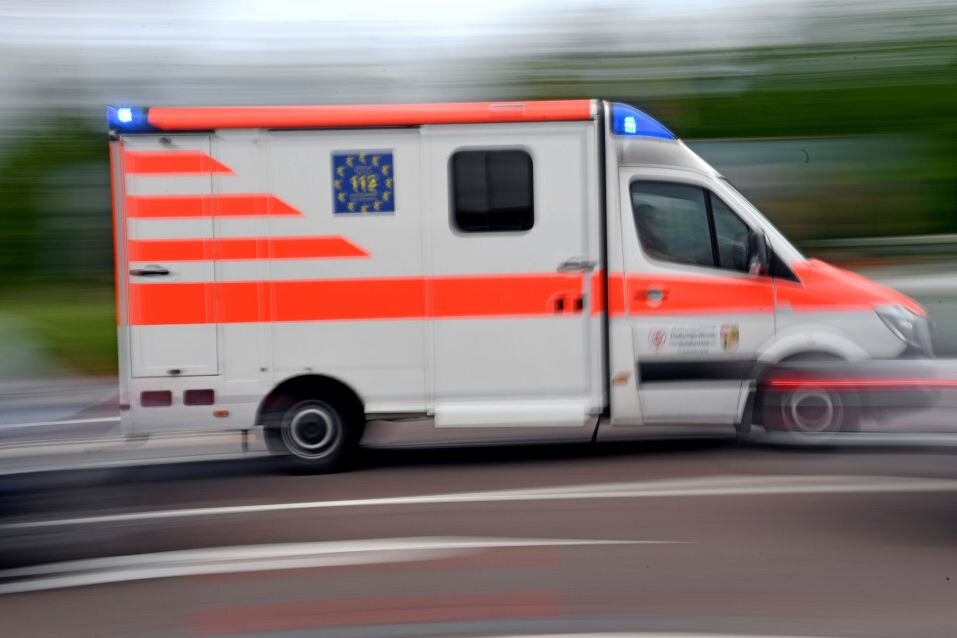Ein Krankenwagen fährt mit Blaulicht auf einer Straße.