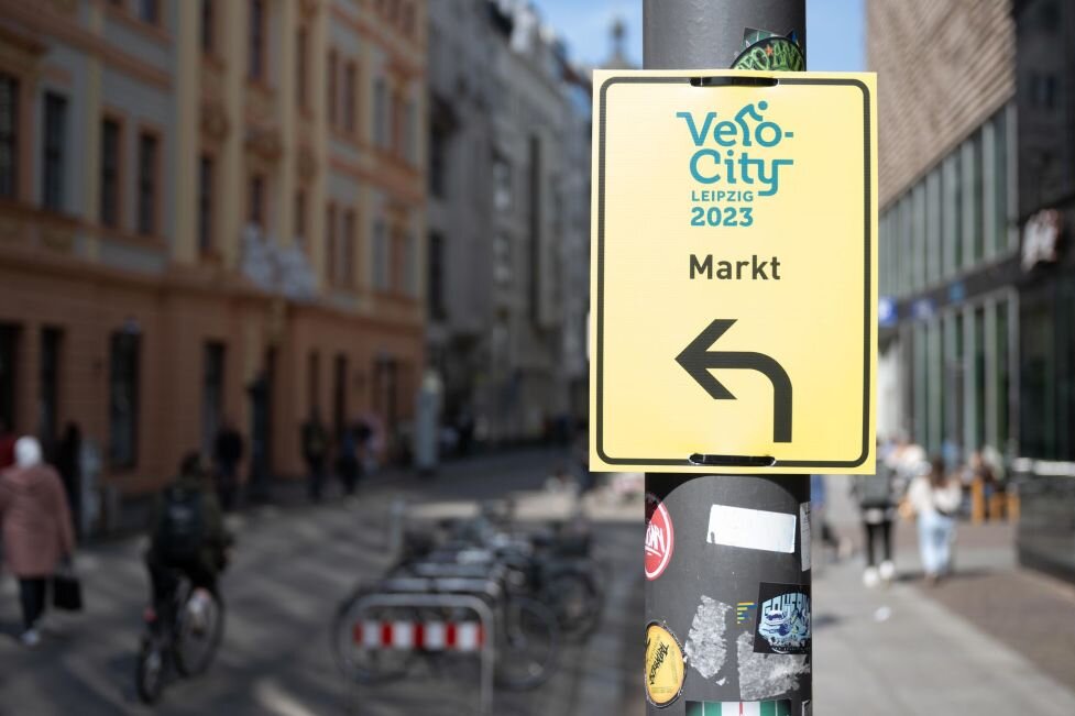 Konflikte auf dem Weg zur Verkehrswende - Ein Schild mit dem Logo des Radverkehrskongresses "Velo-city" markiert einen temporären Radweg im Zentrum von Leipzig.