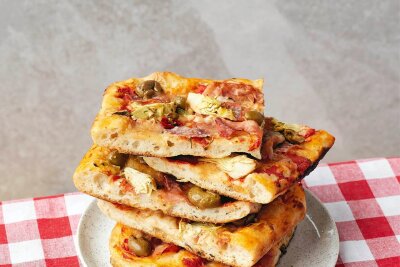 Luftig, knusprig - und vor allem eckig: Pizza vom Blech - Kleine Quadrate von "Pizza in Teglia" sind übereinandergestapelt.