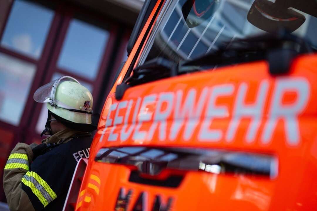 Mensch bei Dresden aus der Elbe gerettet - Eine Einsatzkraft der Feuerwehr steht neben einem Einsatzfahrzeug der Feuerwehr.