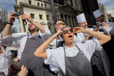 Millionen Menschen sehen totale Sonnenfinsternis - Angestellte eines Restaurants in Manhattan machen eine Pause, um die Sonnenfinsternis zu betrachten.