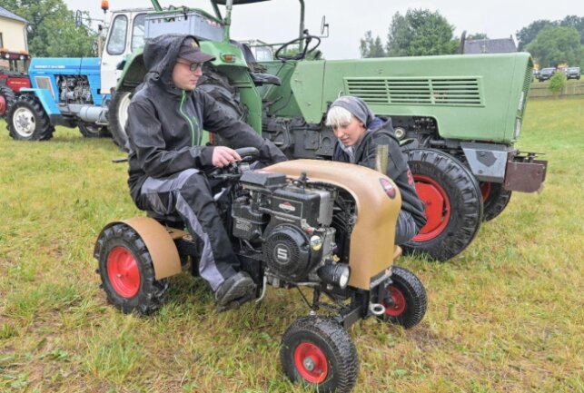 Mit Gummistiefeln und Regenschirm - Christian Schneider (li.) ist mit seinem selbstgebauten Mini-Traktor auf den Festplatz gefahren. Rechts Sarah Uhlig. Foto: Ralf Wendland