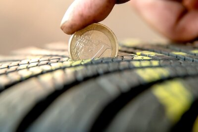 Nachhaltig und sicher: Wann ist ein Reifenwechsel fällig? - Mit einer 1-Euro-Münze lässt sich das Reifenprofil ganz einfach kontrollieren. Der goldene Rand sollte unten nicht aus dem Profil herausragen.