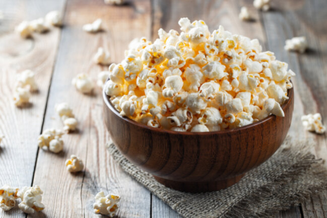 2. Popcorn: Der gepuffte Mais kann ohne schlechtes Gewissen bei einer Diät eingesetzt werden, wenn man diesen nicht in Öl, Butter, Salz oder Zucker ertränkt. Mais enthält eine Menge Ballaststoffe, die für eine gute Sättigung sorgen und den Blutzuckerspiegel regulieren. Anstatt gesüßtes Popcorn zu snacken, sollte man lieber auf die gesalzene Variante zurückgreifen, da diese deutlich weniger Kalorien hat. Am besten ist es, man bereitet sich das Popcorn selbst zu. So kann man genau überprüfen, wie viel Öl/Butter und Salz man einsetzt. Hier eine einfache Schritt-für-Schritt-Anleitung: Nicht jeder Mais kann gepufft werden - nur "Puffmais" ist für die Zubereitung von Popcorn geeignet. Eine beschichtete Pfanne mit Deckel nehmen. Den Boden der Pfanne mit Maiskörner bedecken. Den Deckel auf die Pfanne legen. Den Herd auf die höchste Stufe stellen. Pfanne hin und her bewegen, damit der Mais nicht anbrennt. Hört man das erste Ploppen, kann der Elektro/das Cerankochfeld direkt abgeschalten und ein Gasherd/Induktionskochfeld niedriger gestellt werden. Sobald das Ploppen nachlässt, ist das Popcorn fertig. Je schneller anschließend die Gewürze (Salz, Rosmarin, Paprika und viele weitere) in das Popcorn gemischt werden, desto besser haften diese. 