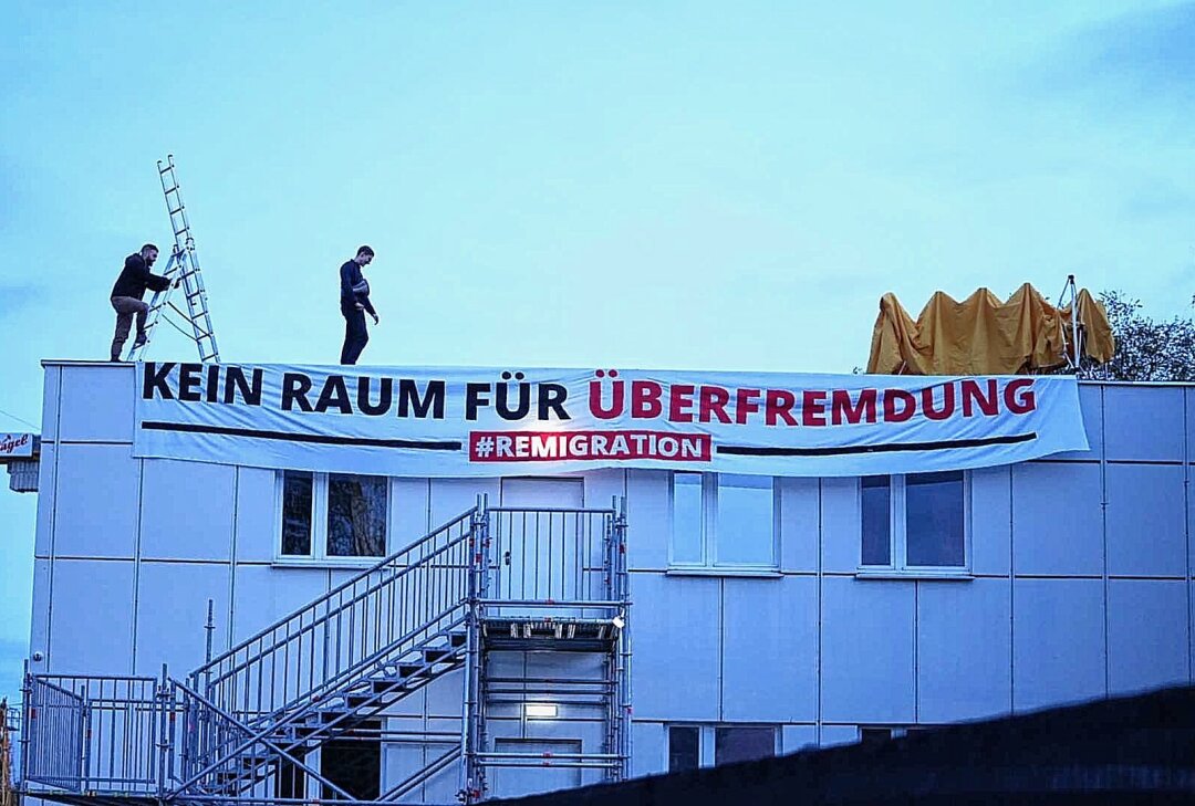 Neonazis besetzen geplante Asylunterkunft - "Kein Raum für Überfremdung": Demonstranten rufen Sprechchöre vom Dach. Foto: xcitepress/Benedict Bartsch