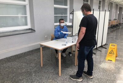 Offizielles Testzentrum im Freiberger Krankenhaus eröffnet - Roland Sapper überreicht einem Besucher sein negatives Testzertifikat. Foto: Claudia Steinbach