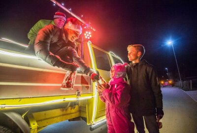 Partybus bringt Weihnachtsstimmung ins Erzgebirge - Im Bild sind v.l. DJ Erzbeat alias Martin Naumann und Bürgermeister Sascha Thamm, die Geschenketüten an Alexandra Adler (7 Jahre) und Max Engmann (10 Jahre) verteilen. Foto: Georg Ulrich Dostmann