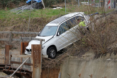 PKW fällt nach Unfall beinah in Abgrund - Gegen 7.10 Uhr kam ein BMW X5 aus bisher ungeklärter Ursache von der Fahrbahn ab, durchbrach einen Bauzaun und landete über einen Gully hinweg in einer Baugrube.