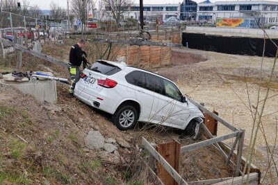 PKW fällt nach Unfall beinah in Abgrund - Gegen 7.10 Uhr kam ein BMW X5 aus bisher ungeklärter Ursache von der Fahrbahn ab, durchbrach einen Bauzaun und landete über einen Gully hinweg in einer Baugrube.