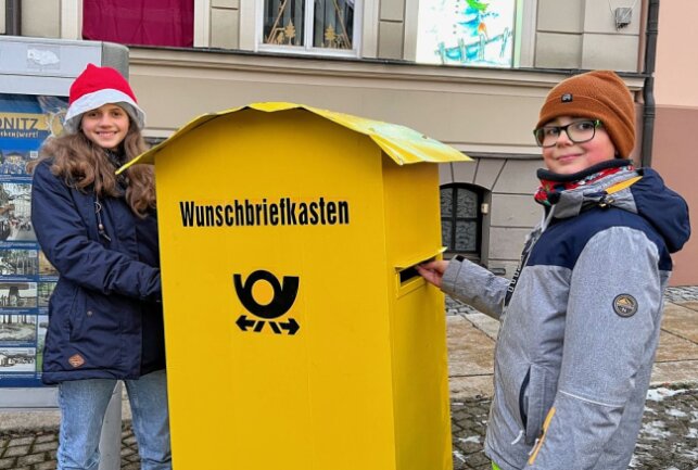 Leonie Pohl (li.) und John Breitfeld (re.) haben ihre Wunschzettel an den Weihnachtsmann in den Wunschbriefkasten in Zwönitz eingeworfen. Foto: Ralf Wendland
