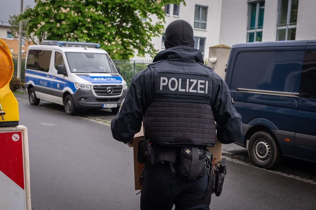 Razzia gegen Schleuser in NRW fortgesetzt - Ein Polizist trägt bei einem Einsatz in Bonn einen Karton mit beschlagnahmtem Material aus einem Gebäude.