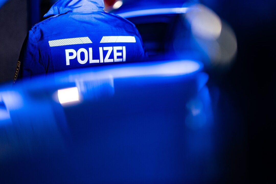 Schlägerei zwischen Fußballfans in Zwickau - Ein Polizist steht neben einem Polizeiauto.