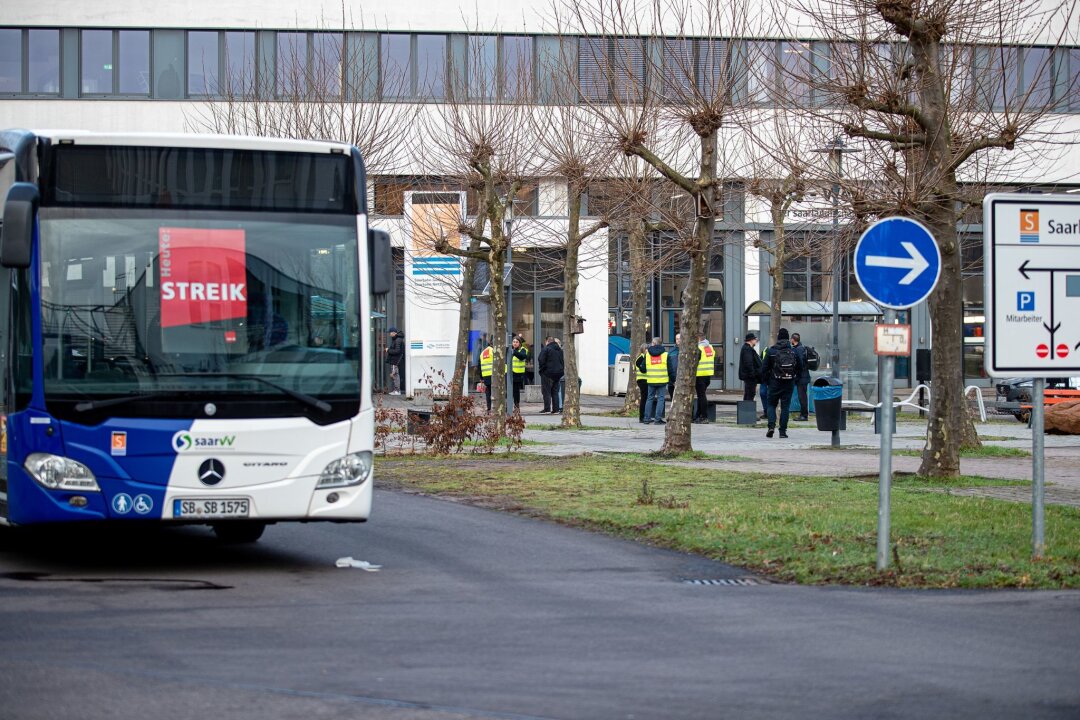 Schon wieder Warnstreiks im ÖPNV in Sachsen: Was man wissen muss - Busse mit Streikplakaten in der Windschutzscheibe und Busfahrer mit gelben Westen.